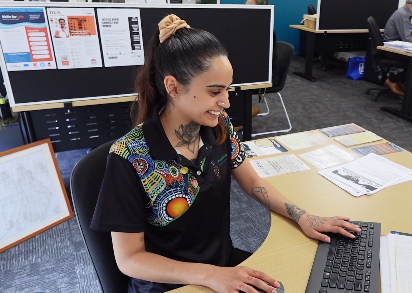 Yilabara team member smiling while working at her desk